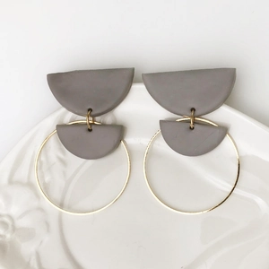 Geometrische polymeerklei oorbellen met gouden metalen ringen op een keramisch bord