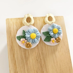 Detailed macro view of 3D handmade polymer clay floral earrings with gold texture