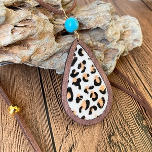 Close-up of leopard print teardrop pendant with wood frame and turquoise bead