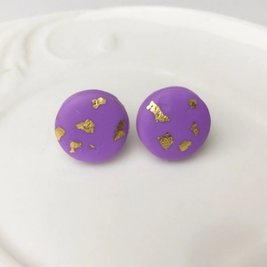 Handmade purple clay stud earrings with gold foil accents on white ceramic tray