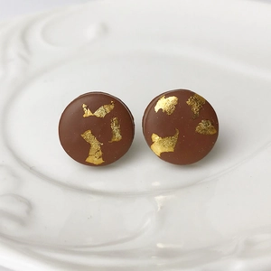 Macro detail of handmade brown polymer clay round stud earrings with gold foil texture