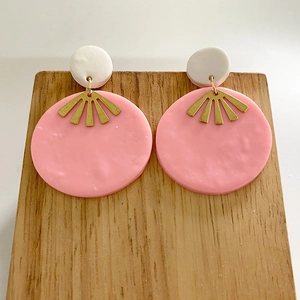 Detail of handmade pink clay earrings with gold metal fan and wooden stand