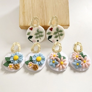 Detail of three pairs of handmade polymer clay earrings with floral patterns and gold metal