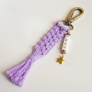 Close-up of handmade purple macrame keychain with LOVE beads, star charm and fringe tassel