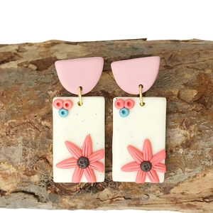 Detail of handmade polymer clay earrings featuring 3D floral accents on a rustic bark base