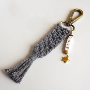 Detail of handmade macrame keychain with grey tassels, Love beads and star pendant