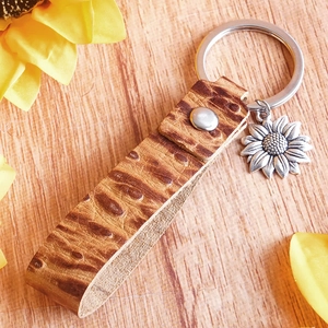 Detail of sunflower leather keychain with giraffe print and silver sunflower metal charm