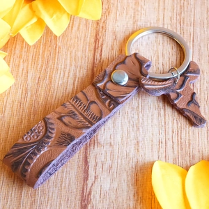 Detail of vintage embossed brown leather keychain with a horse charm on a wooden background