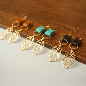 Detail showing leaf-shaped earrings in leather and gold metal finish in three colors