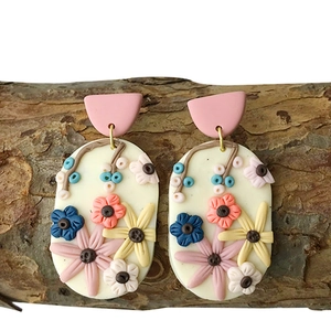 Detailed close-up of handmade clay earrings with 3D floral textures and colorful patterns