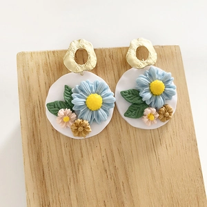 Handmade clay floral earrings with colorful 3D flowers on a wooden jewelry display stand