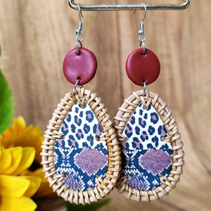 Detail of bohemian drop earrings with leopard print and woven rattan on wood background