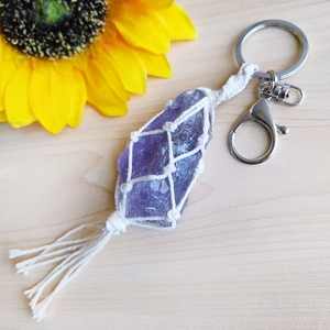 Handmade amethyst stone keychain with white woven mesh and tassels on wooden background