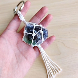 Detail of natural fluorite stone keychain with handmade woven net and long tassel