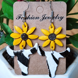Detail of sunflower and zebra print cow head earrings on a jewelry display card
