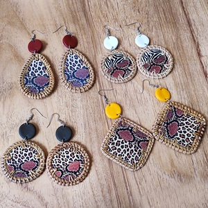 Bohemian rattan woven earrings set with leopard and zebra prints on wooden background