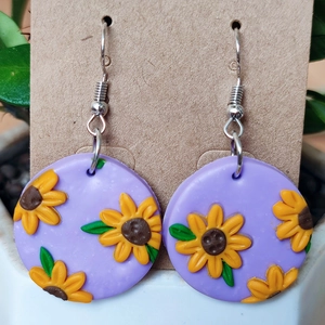 Detalle de pendientes de arcilla polimérica violeta con relieve de girasol hecho a mano