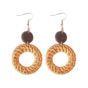 Close-up of handmade round rattan earrings with wooden discs and boho weaving detail