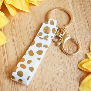 Detail of leopard print leather keychain with gold lobster clasp on wood background