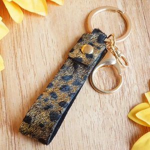 Detail of leopard print leather keychain with golden sequins and metal lobster clasp