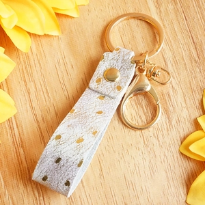 Handmade leather keychain with gold foil dot pattern on a polished gold snap wristlet