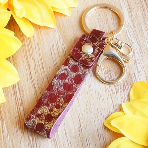 Handmade gold leopard print pony hair leather keychain with metallic ring on wood background