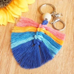 Gros plan du porte-clés bohème arc-en-ciel avec pompon et perle sur fond en bois
