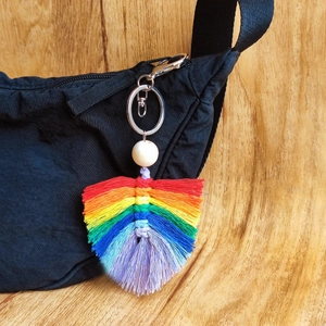 Porte-clés feuille tressée arc-en-ciel avec perle en bois sur un sac à dos noir