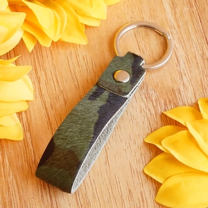 Close-up of camouflage leopard print horsehair leather keychain on a wooden surface