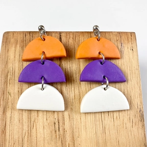 Detailed macro view of the three-layer colorful geometric clay drop earrings on wood