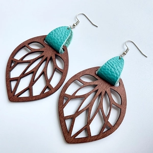 Macro shot of leaf-shaped wood earring with turquoise leather texture and hollow veins