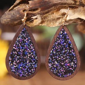 Water-drop wooden earrings with glitter inlay on rustic bark background for Halloween