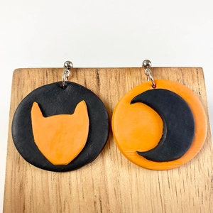 Detail of asymmetrical Halloween clay earrings featuring orange cat and black moon designs