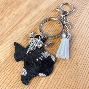 Close-up of Texas-shaped cowhide keychain with a silver bull head charm and white tassel
