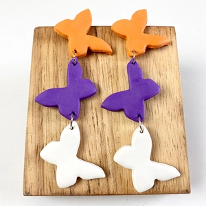 Detailed view of handmade triple butterfly polymer clay drop earrings in orange and purple