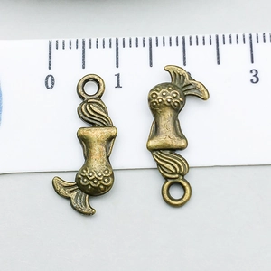 Detailansicht zweier Meerjungfrau-Anhänger aus Bronze mit Lineal als Größenreferenz