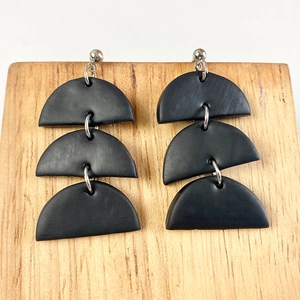 Close-up of geometric matte black polymer clay earrings with triple semicircle layers