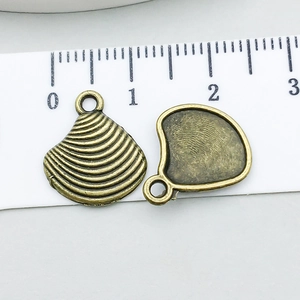 Makro-Detail von antikem Bronze-Muschelanhänger mit Größenskala und Metalltextur