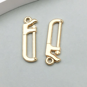 Detail von zwei goldenen Säge-Anhängern für DIY-Schmuck mit polierter Metalloberfläche