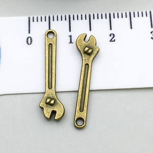 Macro detail of antique bronze wrench charms showing intricate texture and mounting holes