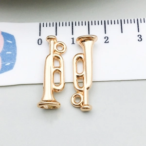 Détail macro de pendentifs trompette en or KC avec règle de mesure pour bijoux DIY