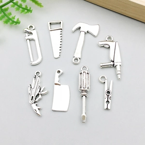 Détail de breloques à outils en argent vintage comme des scies et marteaux pour bijoux DIY