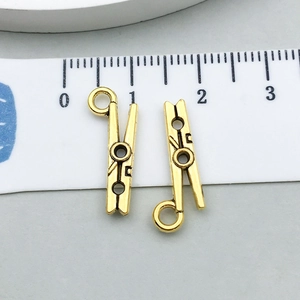 Primer plano detallado de mini colgantes de clip en oro antiguo para joyas con escala