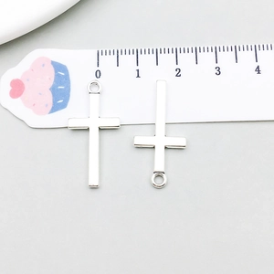 Detail of silver alloy cross pendants showing size measurement on a scale ruler