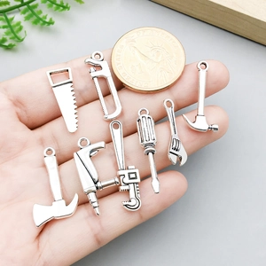 Neuf breloques outils miniatures en alliage argenté dans la main avec pièce de référence