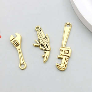 Vista detallada de tres dijes de herramientas en oro para joyería y pulseras DIY