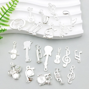 Silver musical instrument charms including guitar and notes on a white display stand