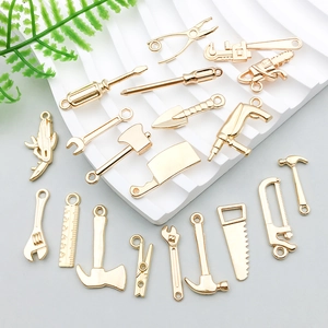 Goldfarbene Werkzeuganhänger wie Schraubenschlüssel und Hammer für DIY-Schmuck