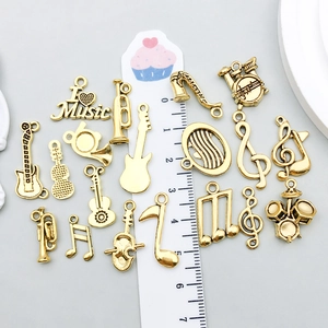 Ensemble de breloques instruments de musique dorés avec guitare et notes sur fond gris