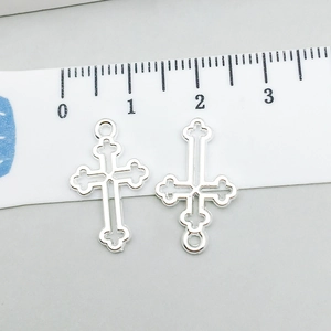Dettaglio di due ciondoli a croce d'argento con un righello per misurare la dimensione